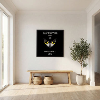 Disapproving Owl Black van Tim Hupkes in een zwarte lijst boven een houten bankje met manden en een olijfboom in een lichte hal