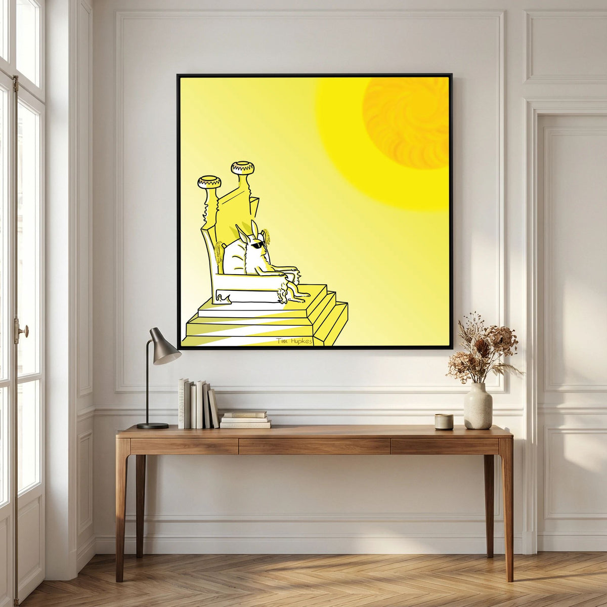 Royal by Tim Hupkes in a black frame hanging above a wooden console desk with lamp and books in a panelled room