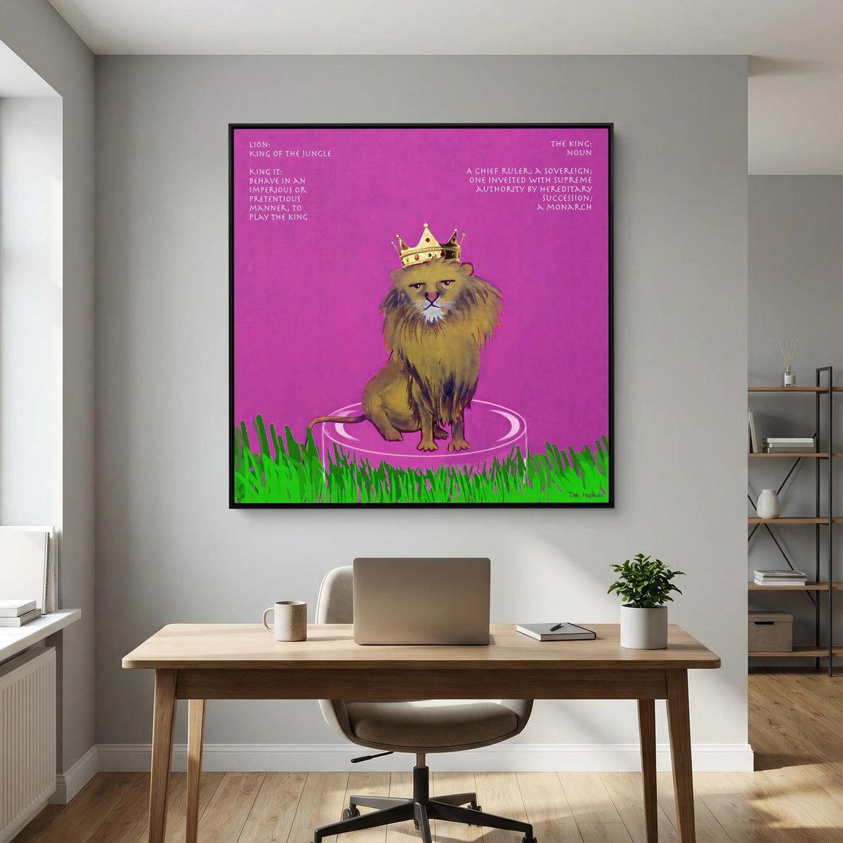 The King canvas print in a black frame above a wooden desk with a laptop in a home office