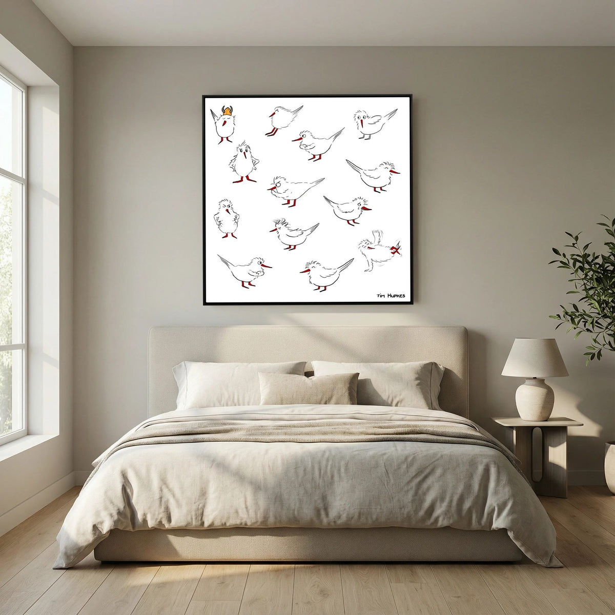 Black-framed Blackburn & Haptoe - everyday heroes by Tim Hupkes above a low double bed with neutral bedding in a quiet bedroom