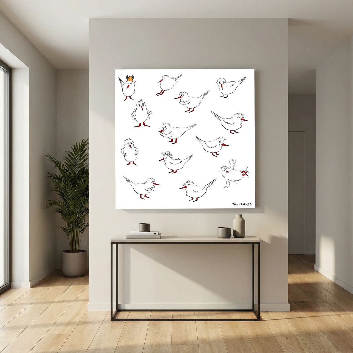 Unframed Blackburn & Haptoe - everyday heroes by Tim Hupkes canvas print above a slim console table in a hallway with a potted plant