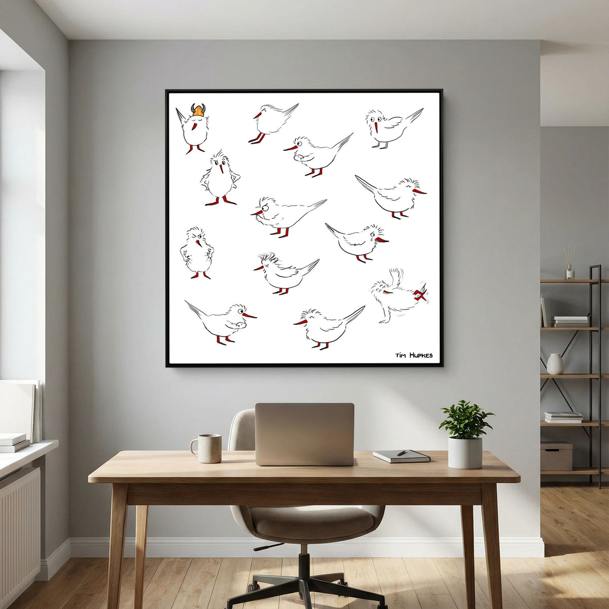 Black-framed Blackburn & Haptoe - everyday heroes by Tim Hupkes on a grey wall above a desk with a laptop, mug and small plant