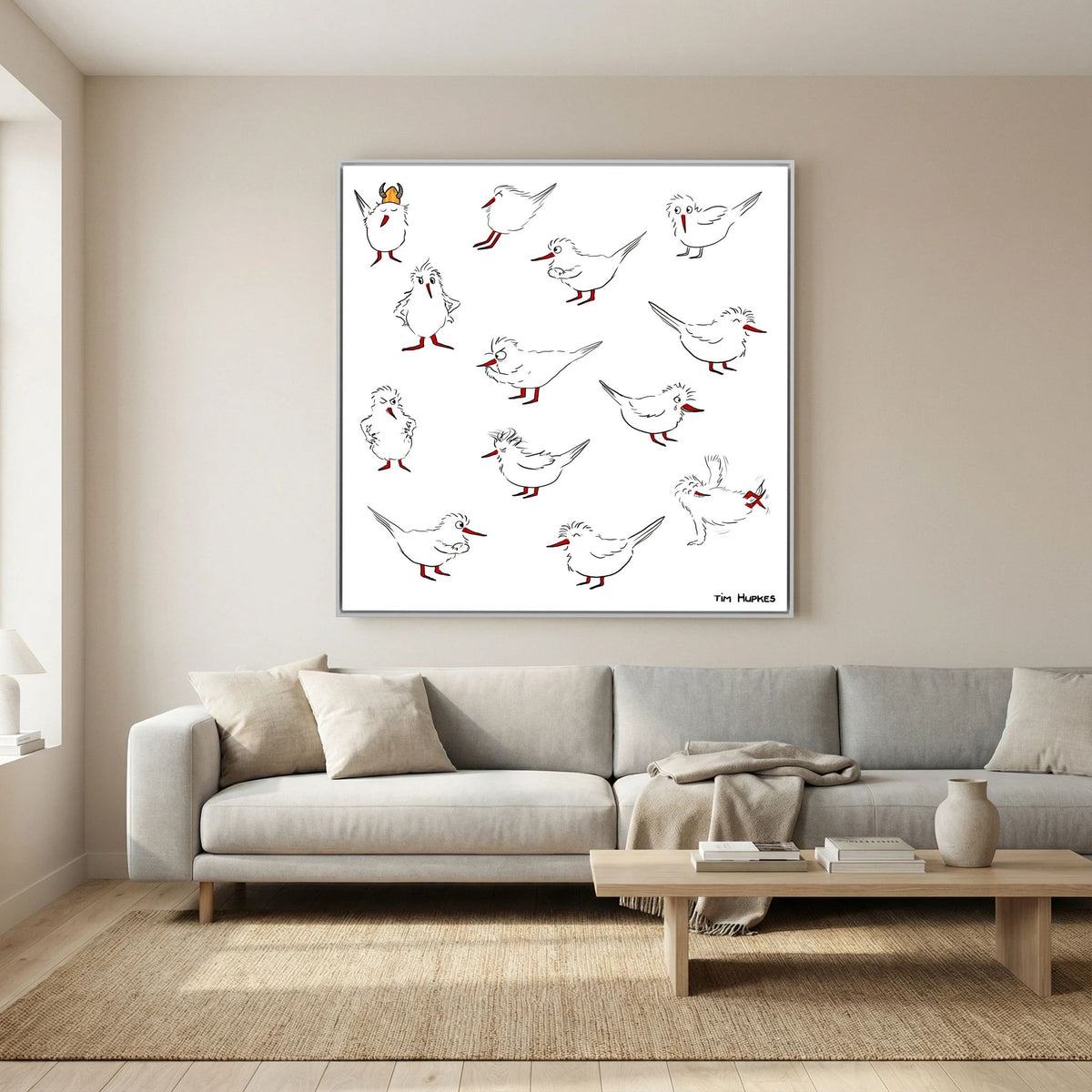 White-framed Blackburn & Haptoe - everyday heroes by Tim Hupkes above a light grey sofa and low wooden coffee table in a calm living room