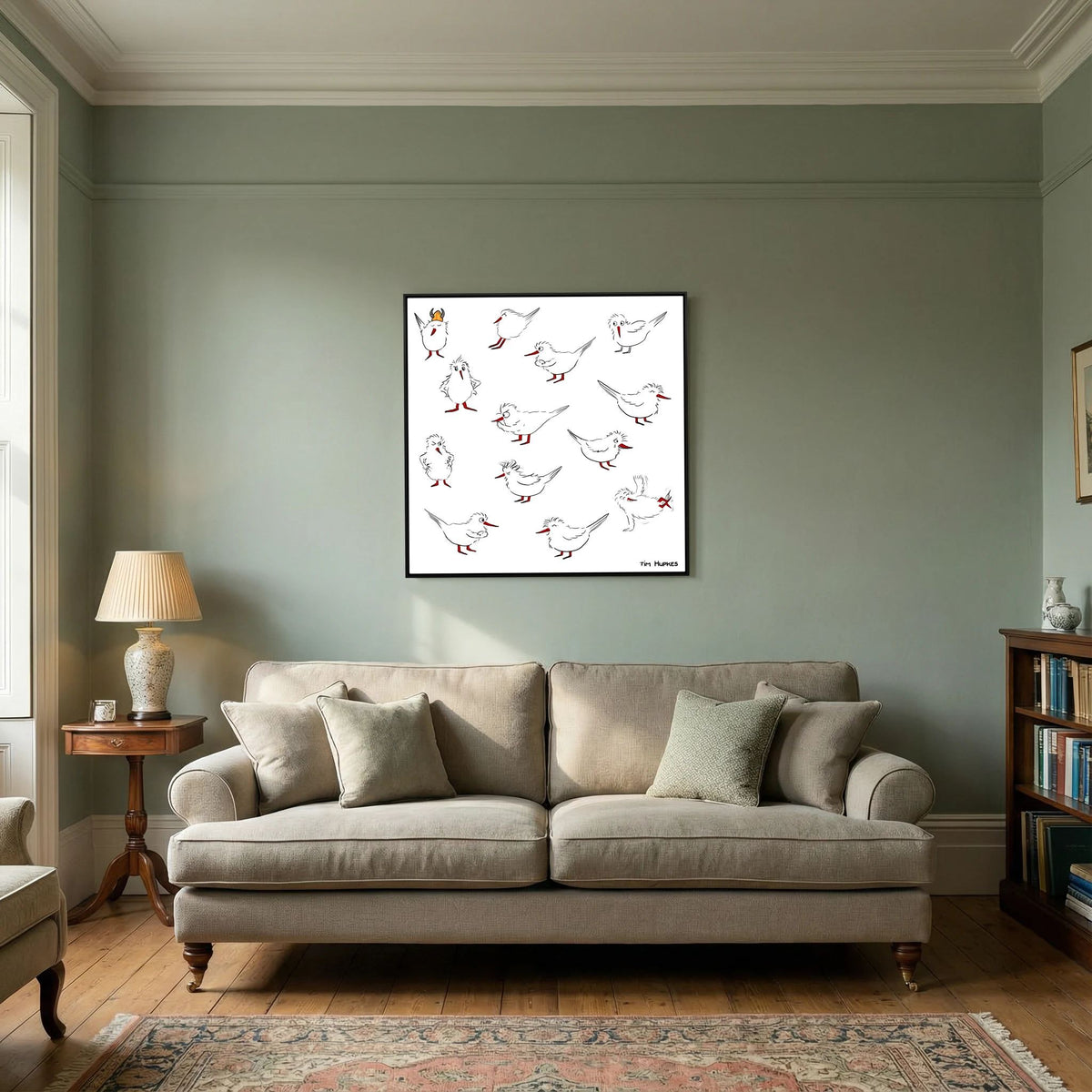 Black-framed Blackburn & Haptoe - everyday heroes by Tim Hupkes on a sage green wall above a beige sofa in a classic living room