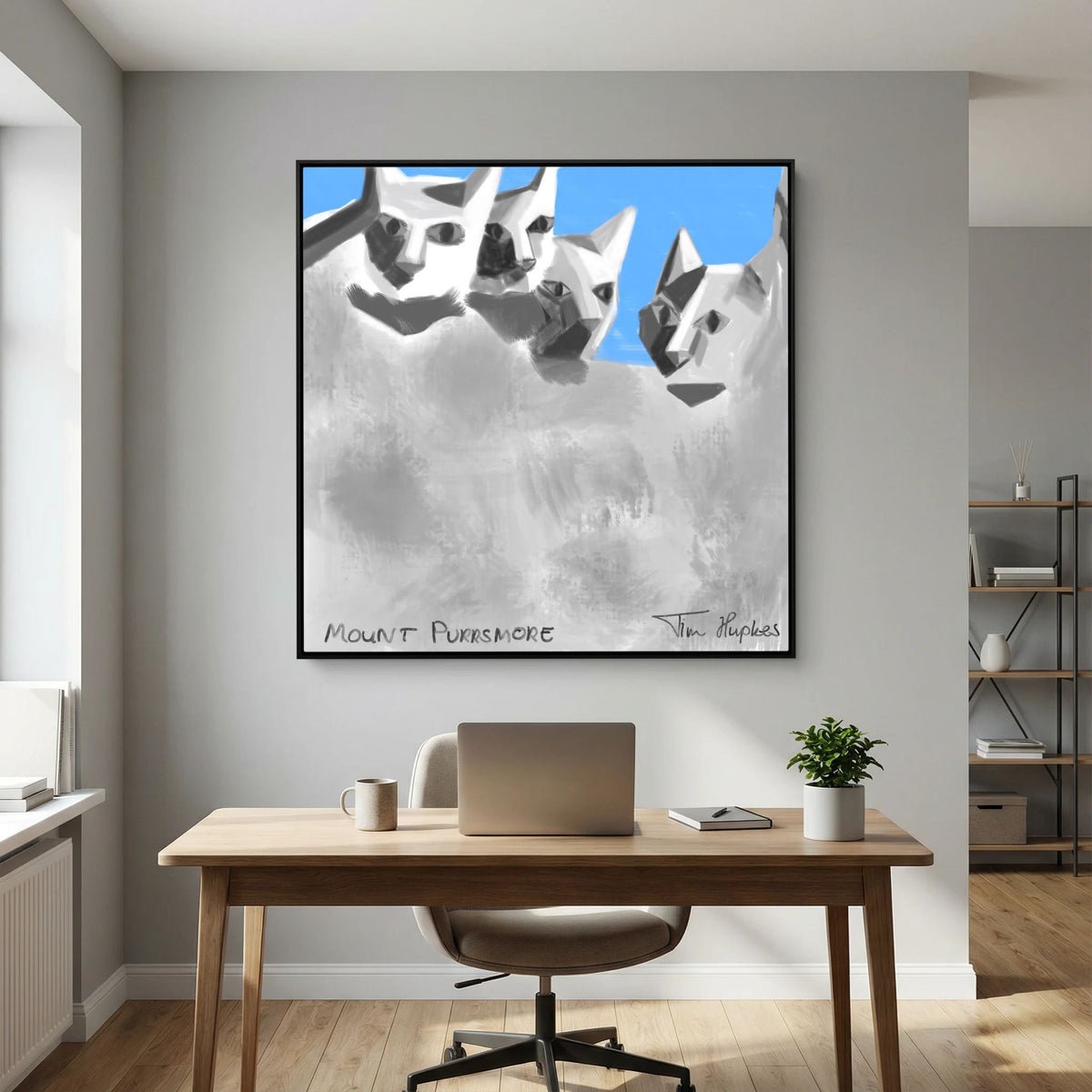 Mount Purrsmore by Tim Hupkes canvas print in a black frame on a grey wall above a wooden desk with a laptop and a pale chair