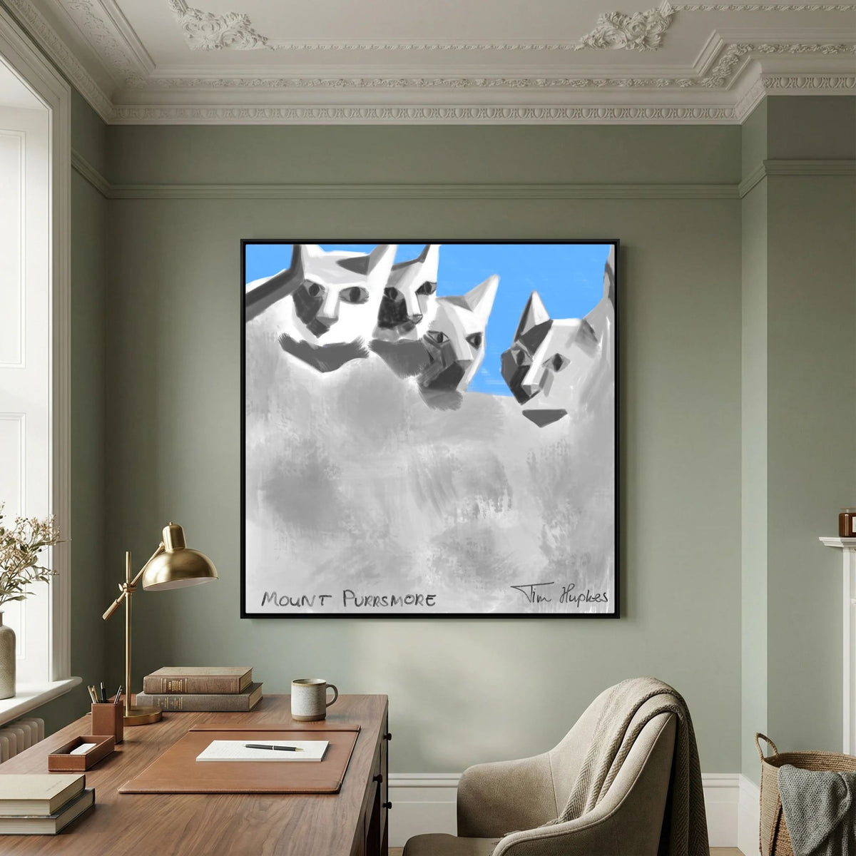 Black-framed Mount Purrsmore by Tim Hupkes canvas print on a green wall above a wooden desk with a brass lamp, books and an armchair