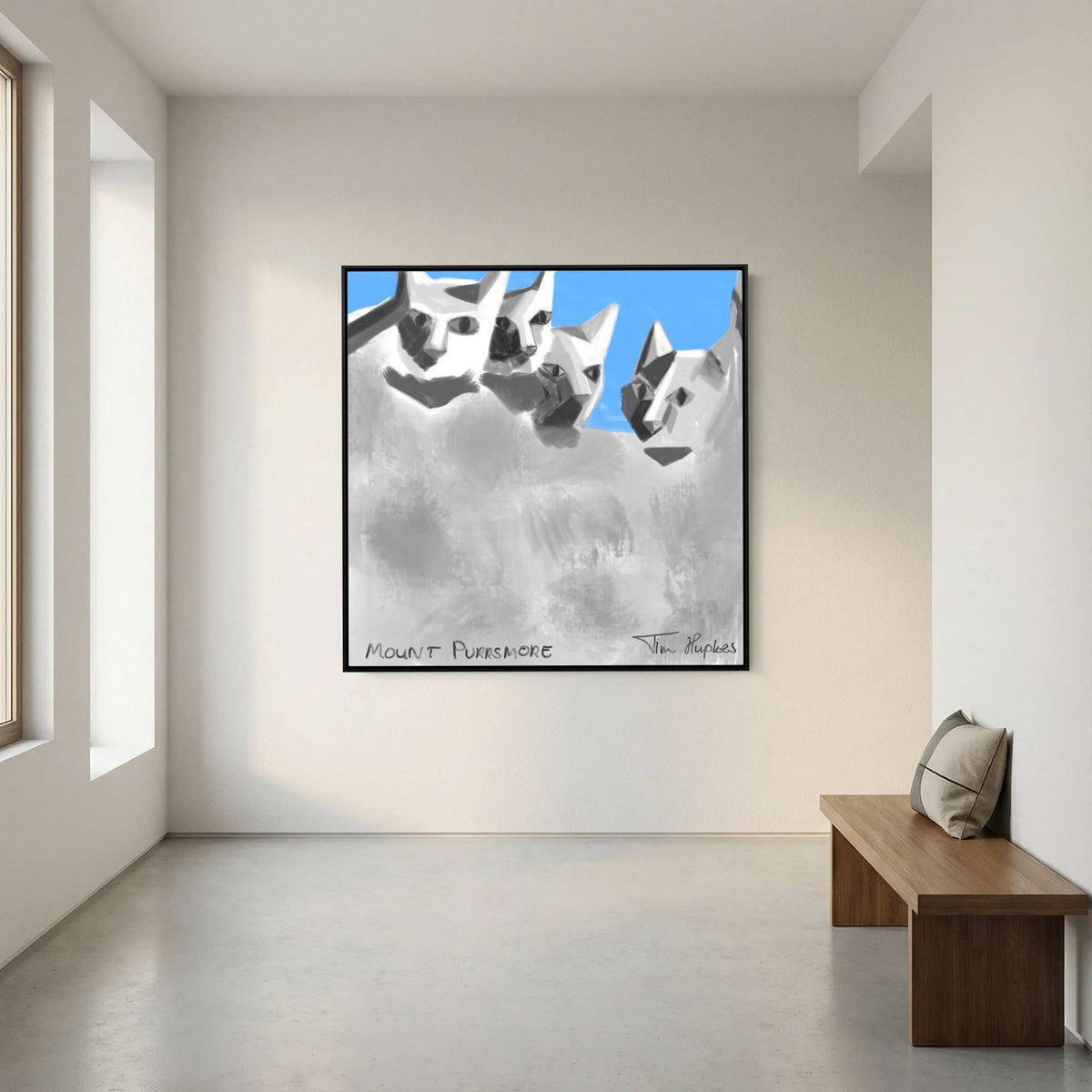 Black-framed Mount Purrsmore by Tim Hupkes canvas print on a white wall in a bright, empty room with a wooden bench and cushion