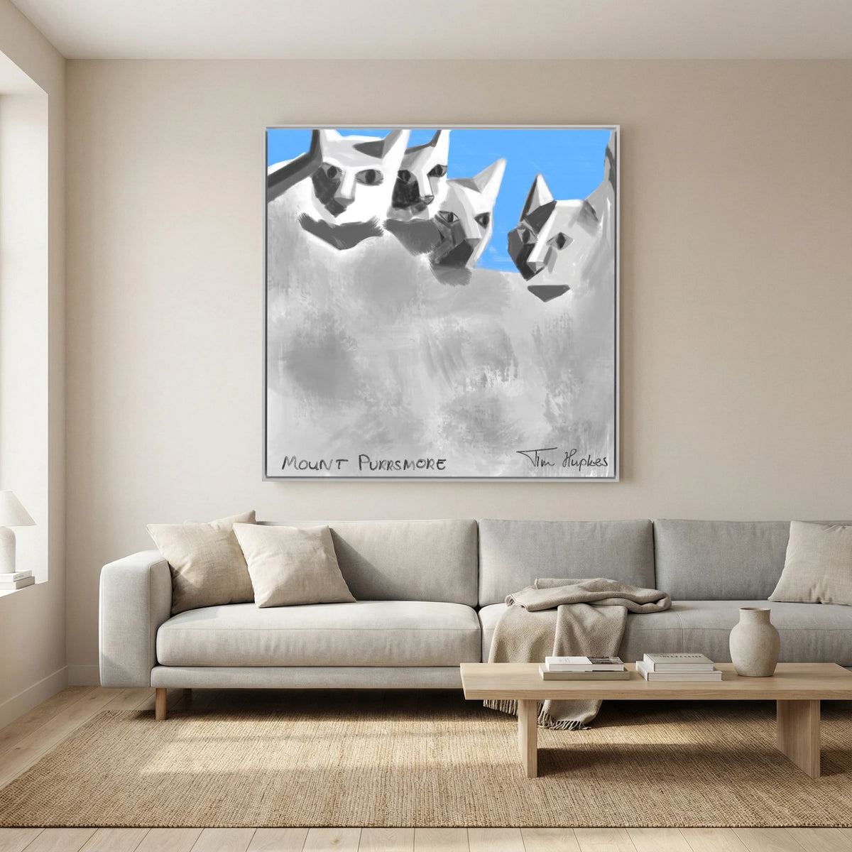 White-framed Mount Purrsmore by Tim Hupkes canvas print above a light sofa with cushions, a low wooden coffee table and a jute rug